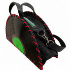A black vinyl record shaped handbag with red contrast stitching, black leather handles, a black zipper, and a bright green center label, shown on a plain white background.