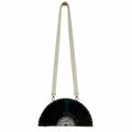 A black vinyl record half-moon shoulder bag with a cream-colored fabric strap and a white geometric pattern on the center, shown against a plain white background.