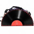 A vinyl record shaped clutch bag with a black vinyl design, red faux-stitching details, a red center label reading 'Sorry I'm not a dancey.', and a dark blue shoulder strap with blue and red patterned lining.