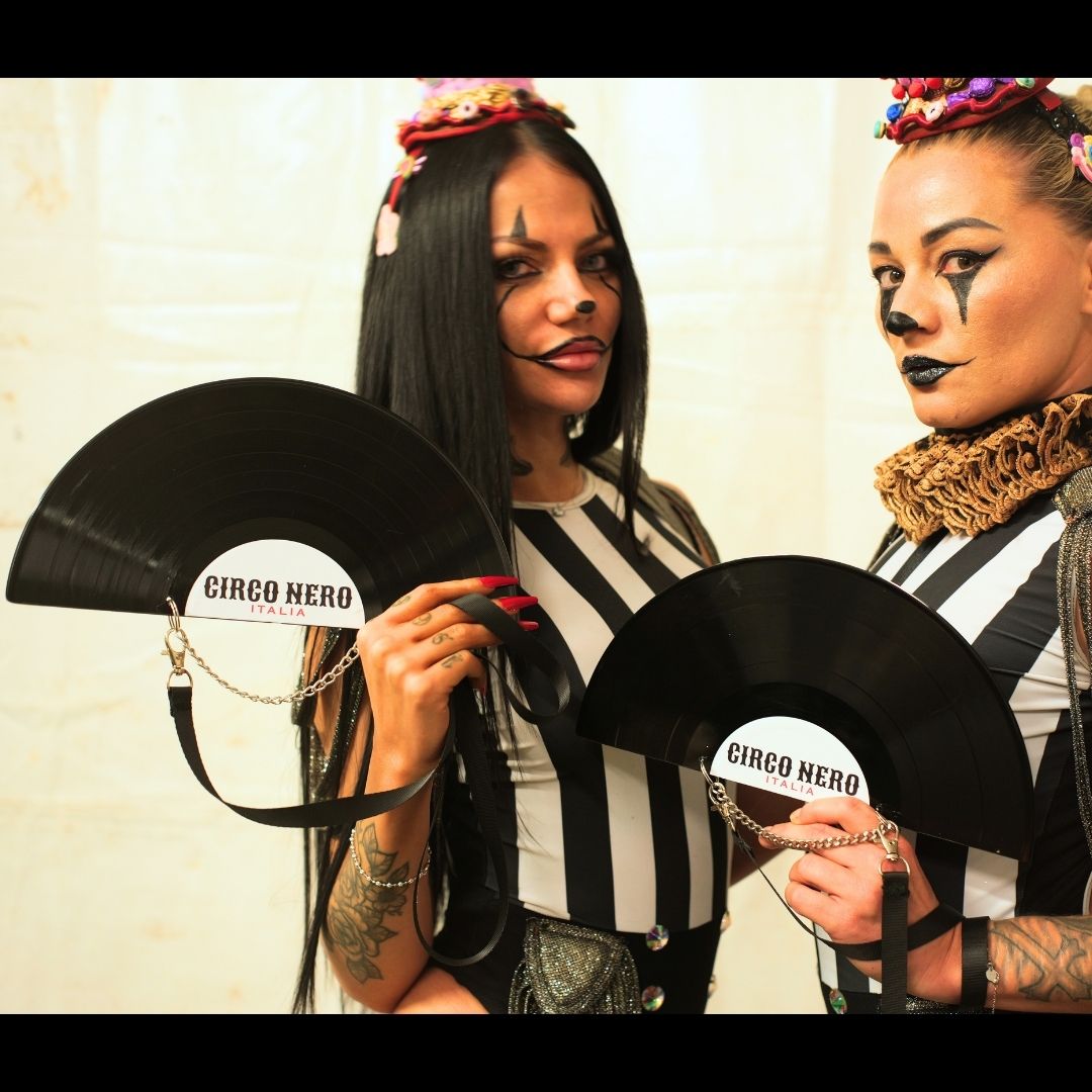 Two women holding black fans with 'Circo Nero' branding against a neutral background.