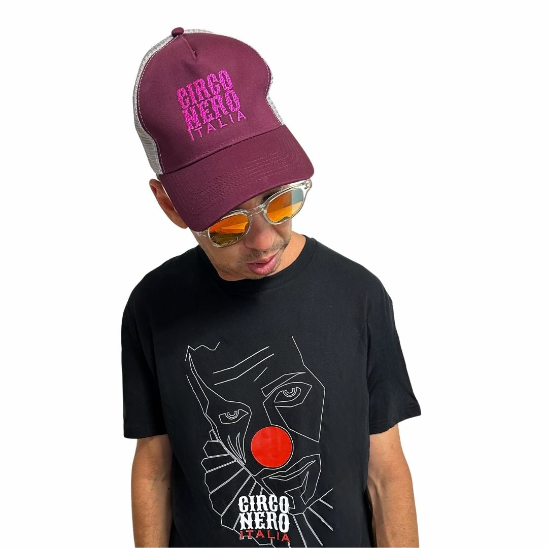Person wearing a maroon 'Circo Nero Italia' cap and black t-shirt with graphic design on a white background