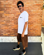 francesca farfa t shirt. Man wearing a white t-shirt and brown shorts standing against a wooden wall.