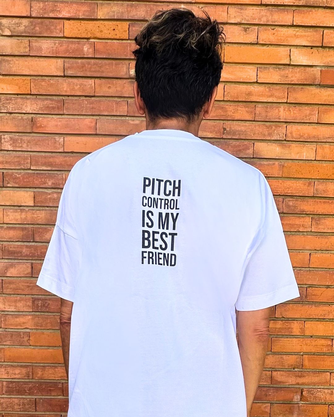 francesca farfa t shirt. Man wearing a white t-shirt and brown shorts standing against a wooden wall.