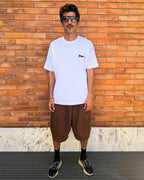 francesca farfa t shirt. Man wearing a white t-shirt and brown shorts standing against a wooden wall.
