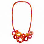 A vibrant multicolor braided necklace with a circular ring pendant cluster, featuring shades of orange, red, pink, and yellow on a plain white background. Silvia Tolomei best handmade jewelry in Tuscany. Tuscany jewelry. Tuscan jewelry. Populonia best store to visit. Things to do in populonia. 