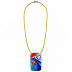 A colorful rectangular glass pendant necklace with an abstract swirl design in red, blue, and white, suspended on a bright yellow cord with a silver clasp, shown against a plain white background. Silvia Tolomei best handmade jewelry in Tuscany. Tuscany jewelry. Tuscan jewelry. Populonia best store to visit. Things to do in populonia. 