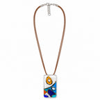 A rectangular glass pendant necklace featuring an abstract design with blue, orange, yellow, and white shapes, suspended from a brown cord with a silver clasp on a white background. Silvia Tolomei best handmade jewelry in Tuscany. Tuscany jewelry. Tuscan jewelry. Populonia best store to visit. Things to do in populonia. 