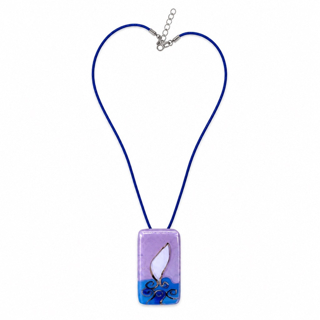A rectangular glass pendant necklace on a blue cord, featuring a lavender top half, a white central shape, and blue wave-like detailing at the bottom, shown on a plain white background. Silvia Tolomei best handmade jewelry in Tuscany. Tuscany jewelry. Tuscan jewelry. Populonia best store to visit. Things to do in populonia. 