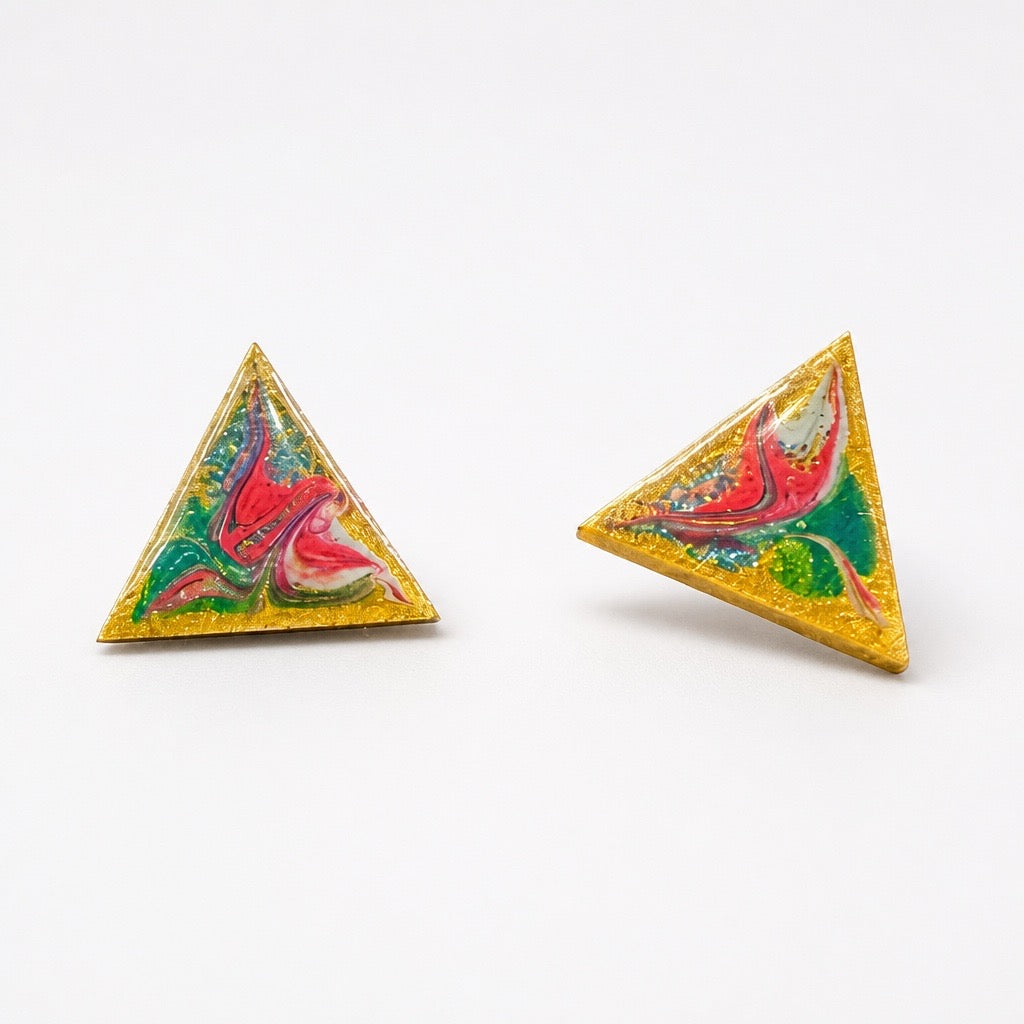 Two triangular gold glitter stud earrings with colorful marbled resin designs in red, green, pink, and white, displayed on a clean white background. Silvia Tolomei best handmade jewelry in Tuscany. Tuscany jewelry. Tuscan jewelry. Populonia best store to visit. Things to do in populonia. 