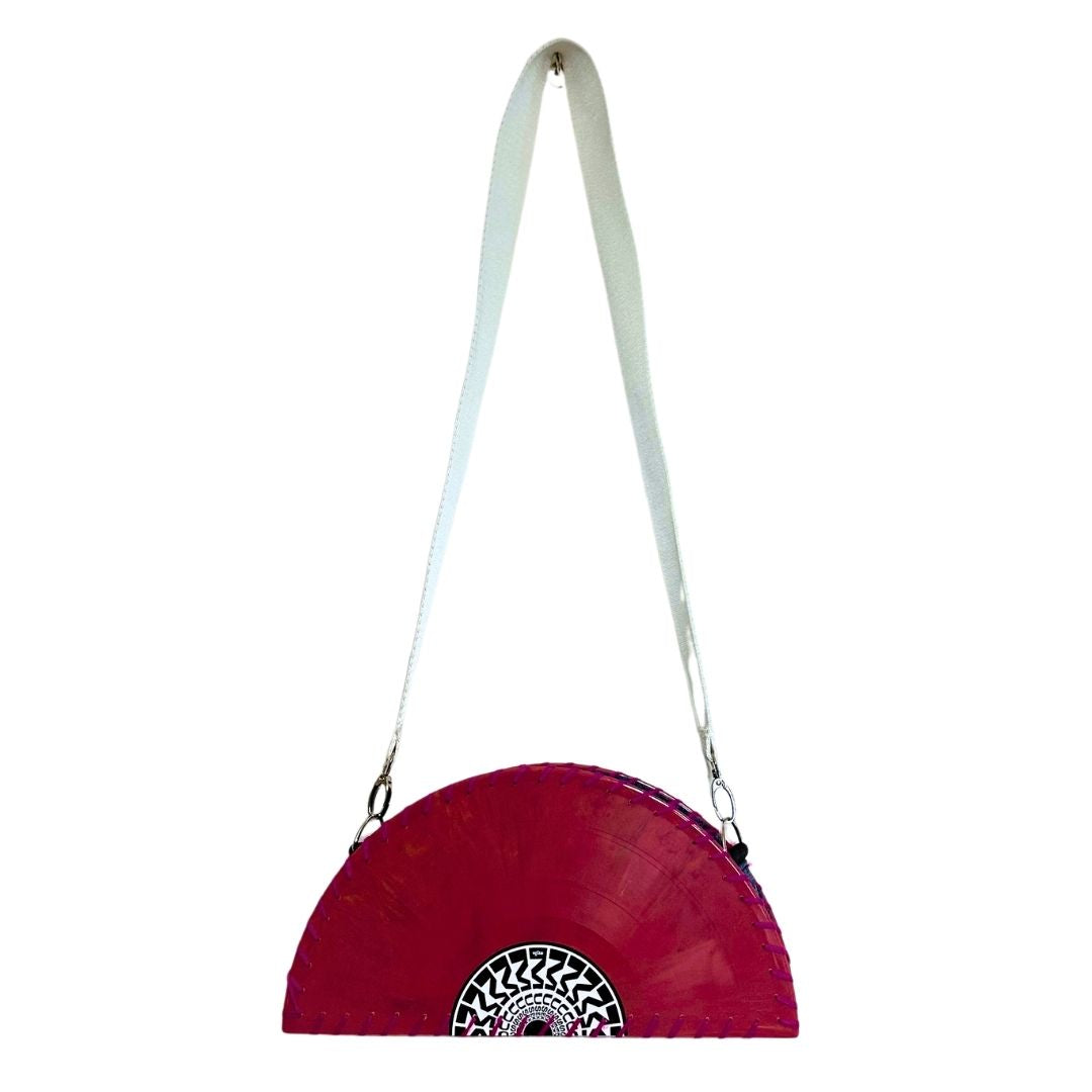 A red vinyl record half-moon shoulder bag with a white strap and a black and white circular graphic at the bottom, shown against a plain white background.