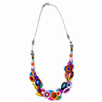 A vibrant statement necklace featuring colorful circular and striped beads on a silver chain, displayed against a solid white background. Populonia jewelry by Silvia Tolomei necklace