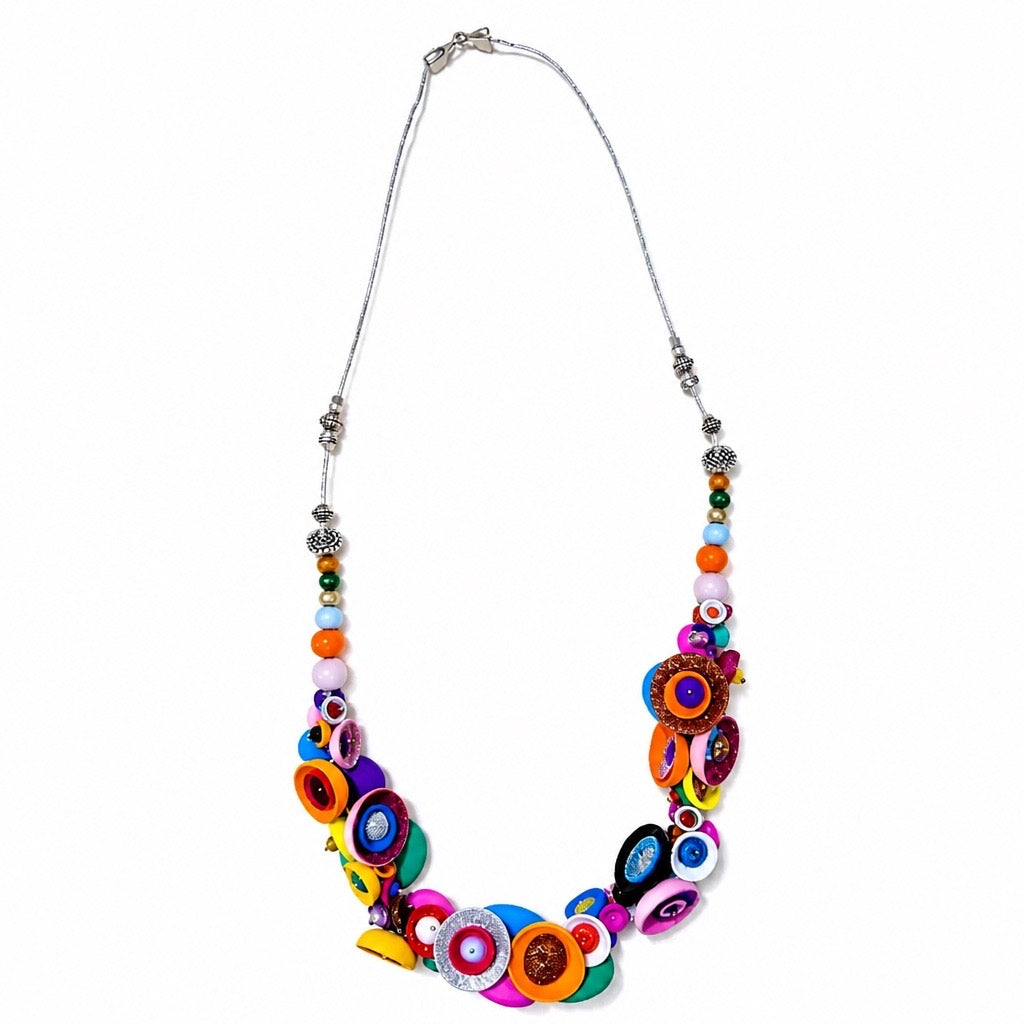 A vibrant statement necklace featuring colorful circular and striped beads on a silver chain, displayed against a solid white background. Populonia jewelry by Silvia Tolomei necklace