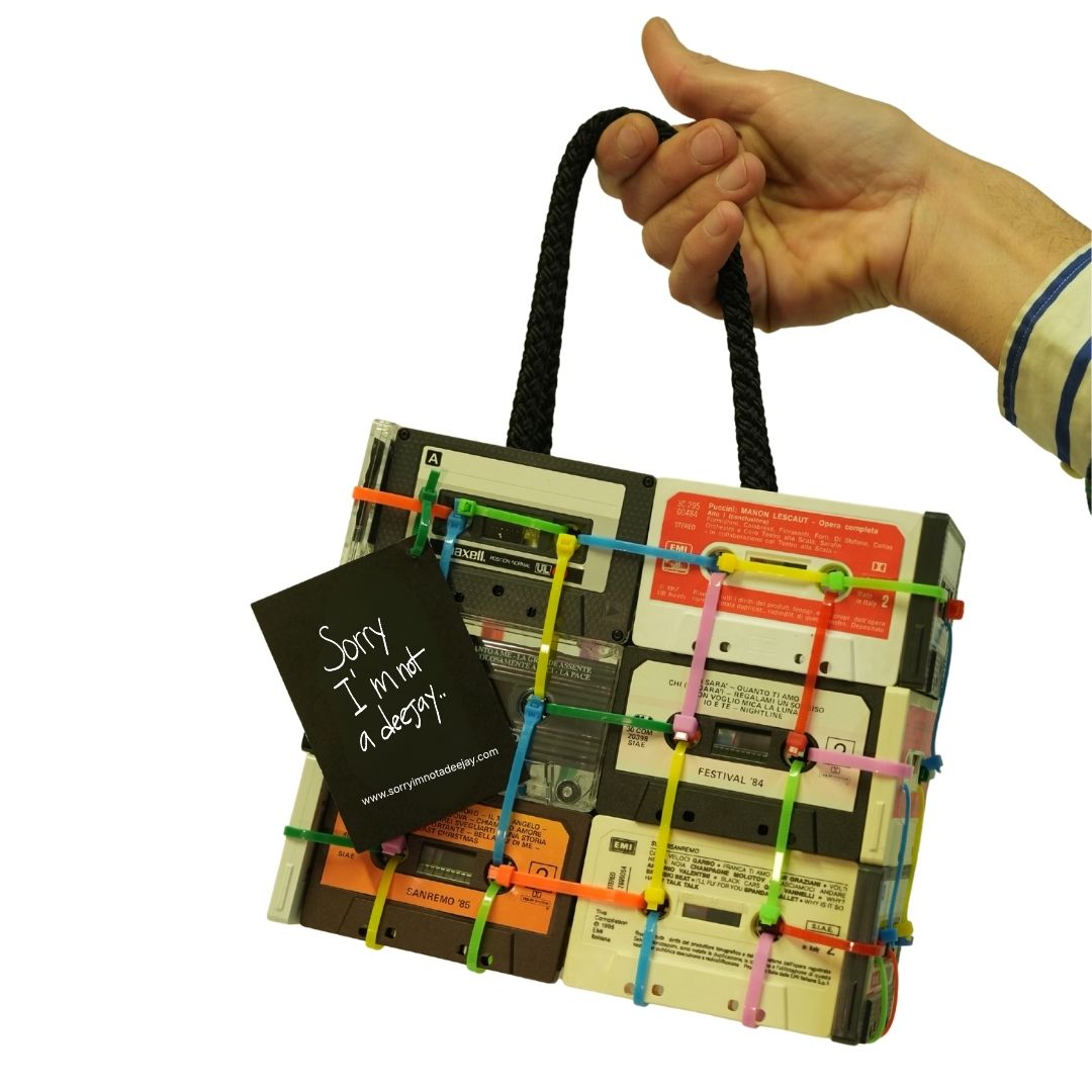 Handbag made from recycled cassette tapes with colorful straps, held by a hand.