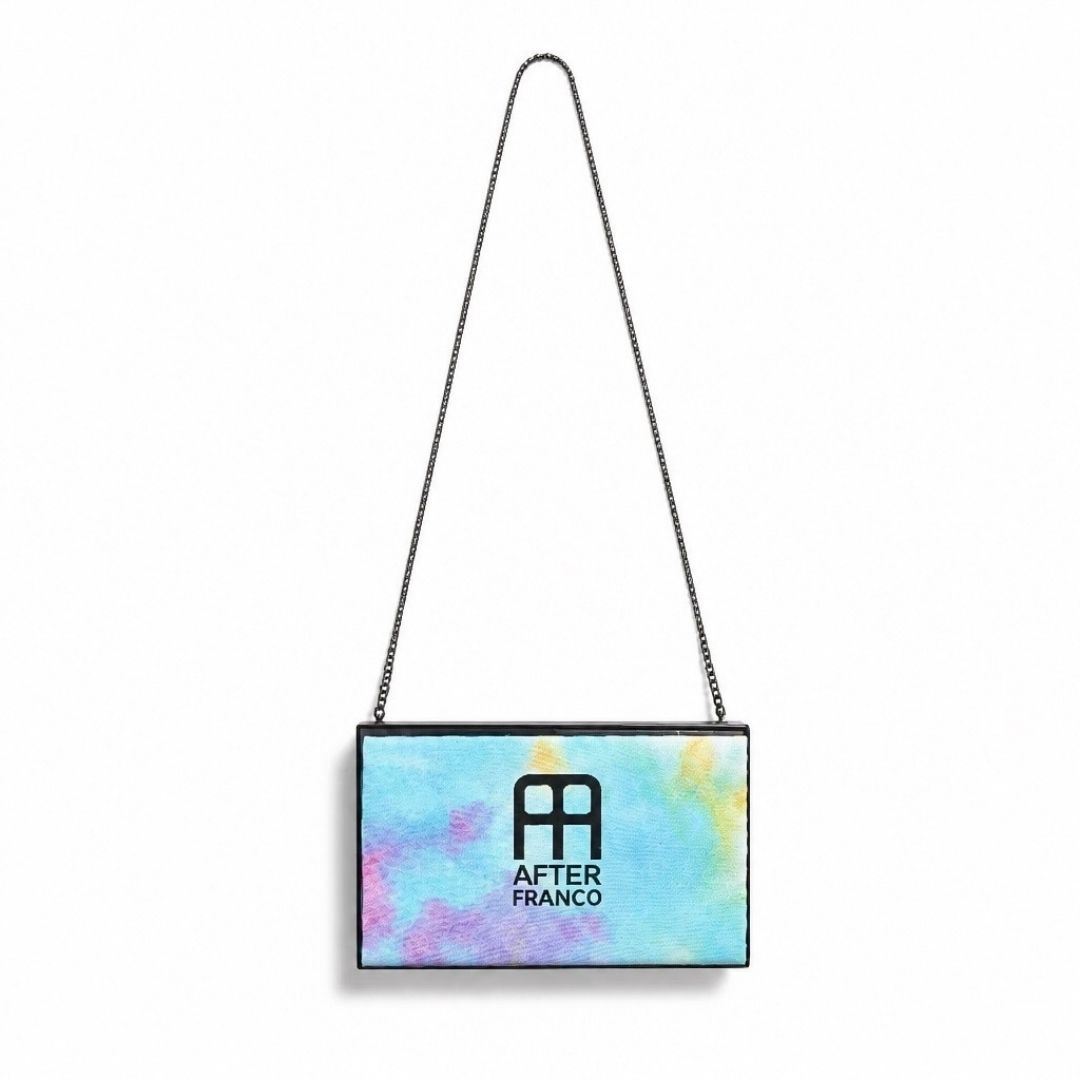 A rectangular handbag with a colorful pastel watercolor pattern in shades of blue, pink, and yellow, featuring a black chain strap and the After Franco logo printed on the front.