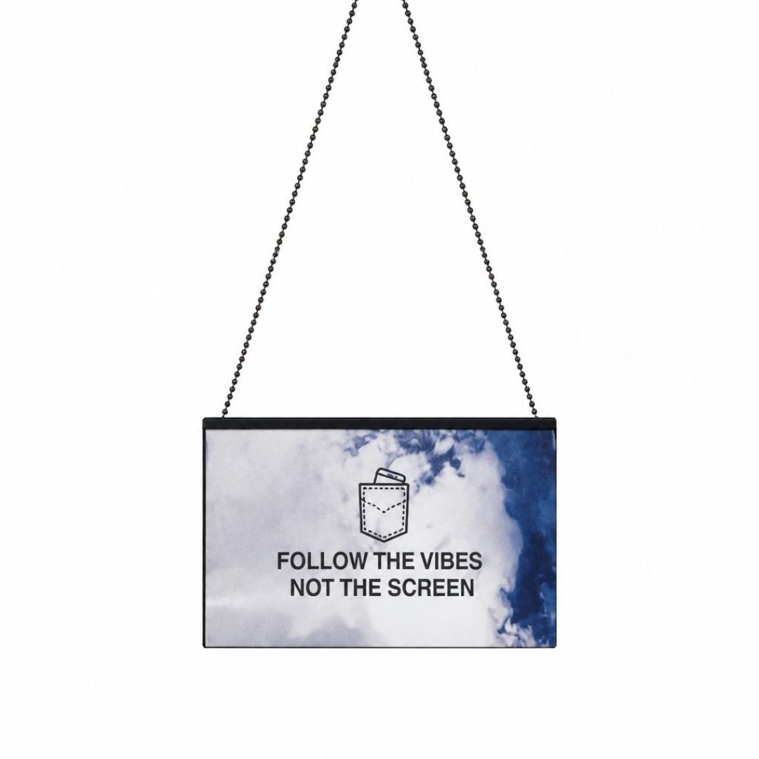 A rectangular hanging wall sign with a black ball chain, featuring a blue and white watercolor design and the text 'FOLLOW THE VIBES NOT THE SCREEN' with a small pocket graphic above it, shown on a plain white background.
