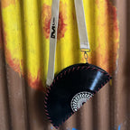 A black vinyl record bag with red stitching and a white patterned center, hanging from a white shoulder strap with a black 'M USK' logo, set against a yellow and brown corrugated metal background.