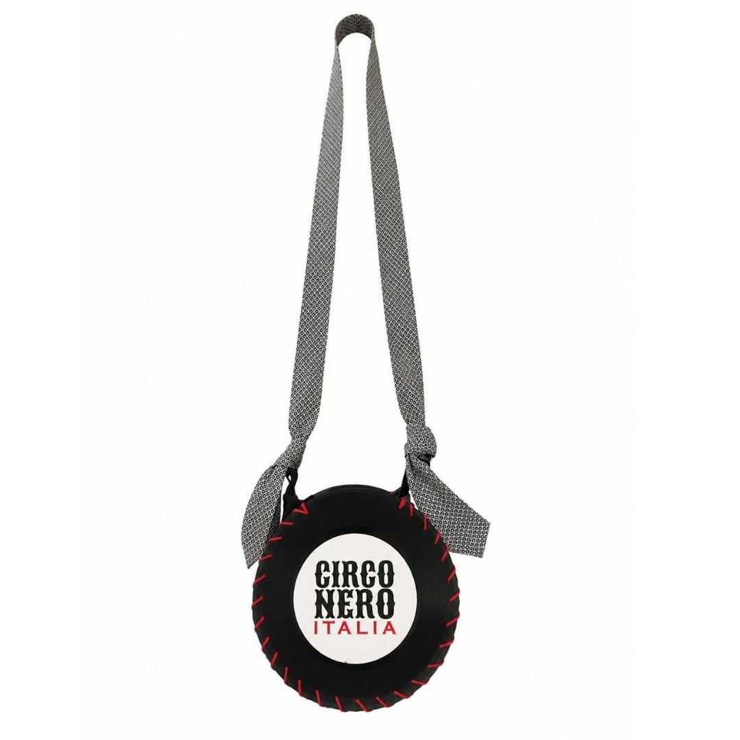 A circular black leather crossbody bag designed like a baseball, featuring red stitching details, a white center with the text 'CIRCO NERO ITALIA' in black and red, and a gray patterned shoulder strap.