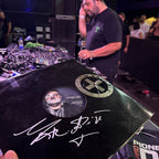 Person holding a vinyl record with a signature in a DJ setting. andrea decuzzi mario piu
