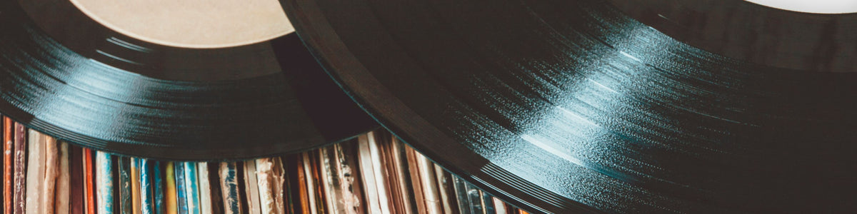 Close-up of black vinyl records stacked on top of a row of colorful record sleeves.