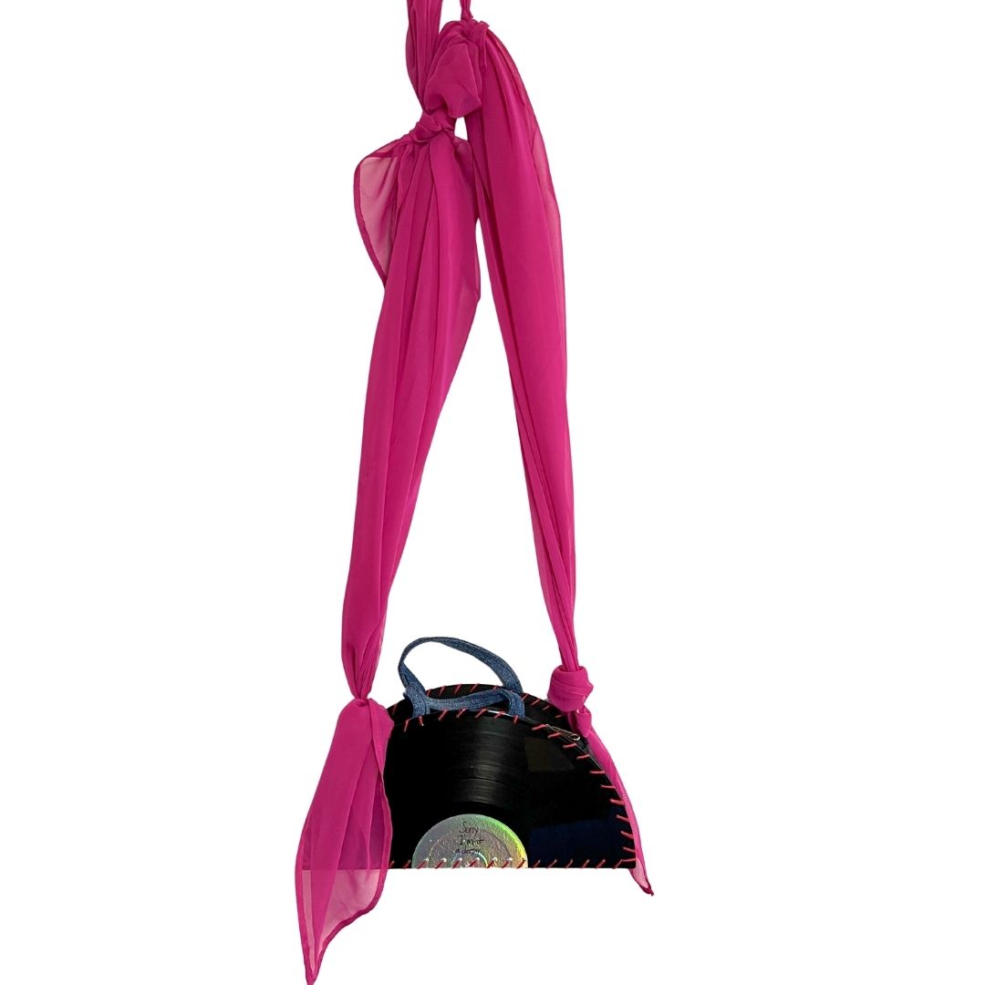 A bright pink sheer scarf-style shoulder bag with a knotted top and long draped straps, shown against a plain white background.